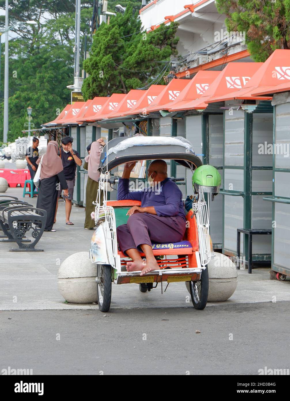 Yogyakarta, Indonesien - November 20 2021 : Becak ist ein traditionelles Transportmittel. Der Becak-Fahrer wartet auf einen Kunden, während er sitzt Stockfoto