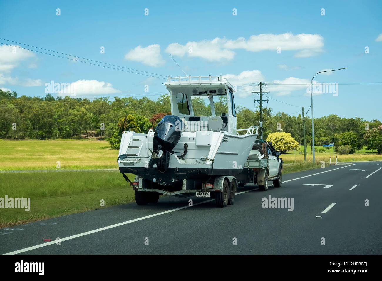 Bruce Highway, Proserpine, Queensland, Australien - Dezember 2021: Ein Motorboot auf Anhänger, das von einem kleinen Lastwagen auf einer Landstraße geparkt wird Stockfoto