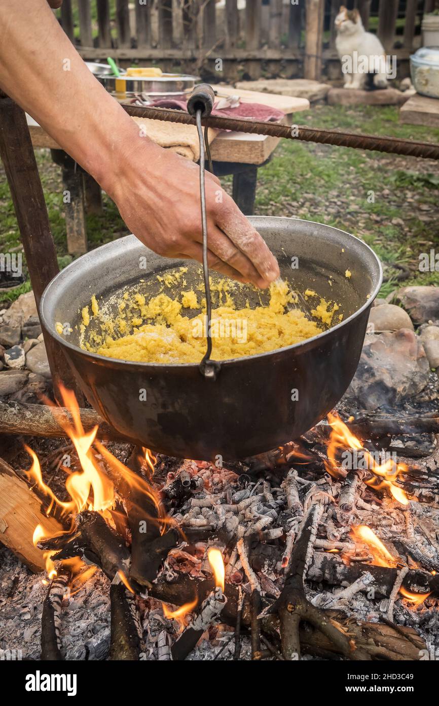 Polenta oder Mammaliga kochen auf offenem Feuer in einem großen Topf. Stockfoto