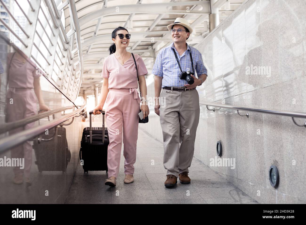 Älteres asiatisches Paar mit einer Frau, die einen Koffer schleppt und glücklich mit einem Lächeln auf dem Flughafen spricht, um sich auf die Reise vorzubereiten. Das Glück der Tanten und Ungl Stockfoto