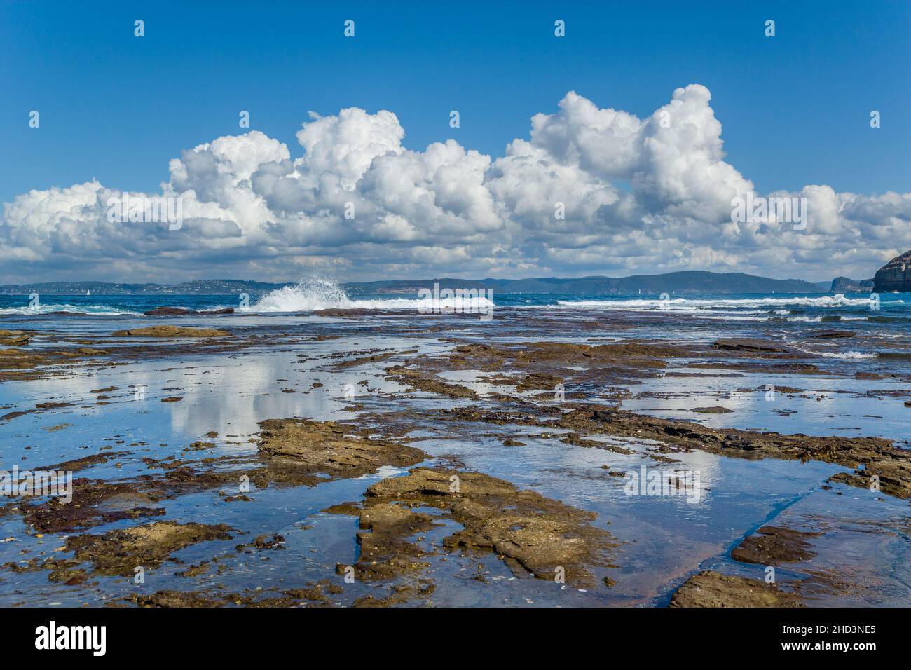 Wolken spiegeln sich in den Pools und Pfützen der Felsplattform am Bouddi Point, im Bouddi-Nationalpark, an der Central Coast, in New SouhWales, Australien Stockfoto