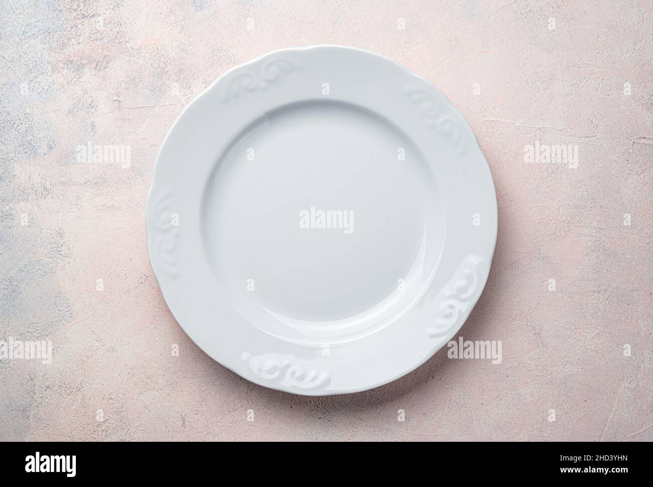 Eine leere weiße Platte auf einem hellrosa Hintergrund. Stockfoto