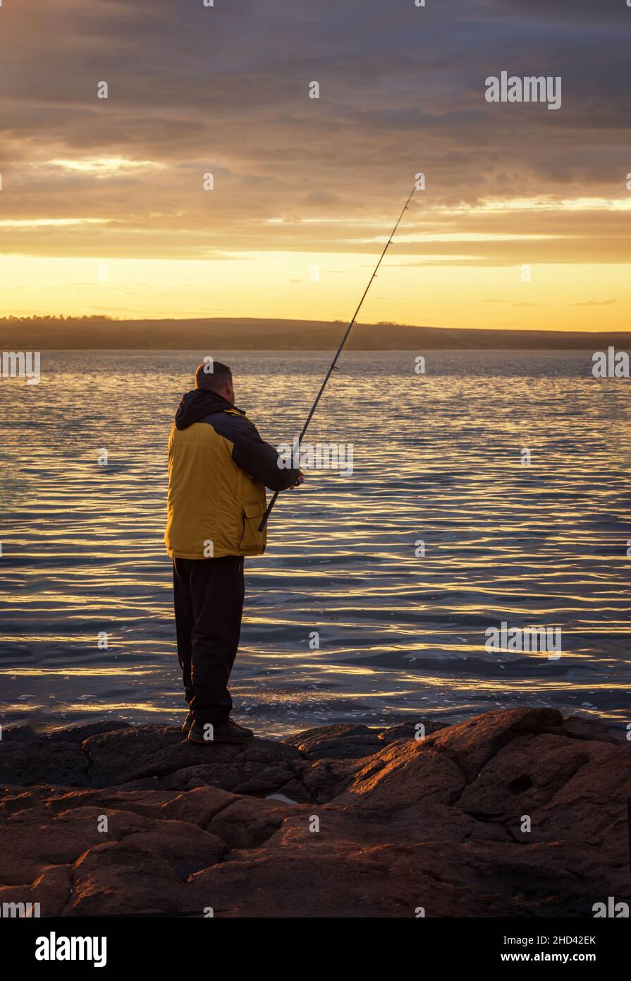 Eine Fischersilhouette beim Fischen bei Sonnenuntergang. Süßwasserfischen, Fischfang. Angeln Spinning bei Sonnenuntergang. Stockfoto