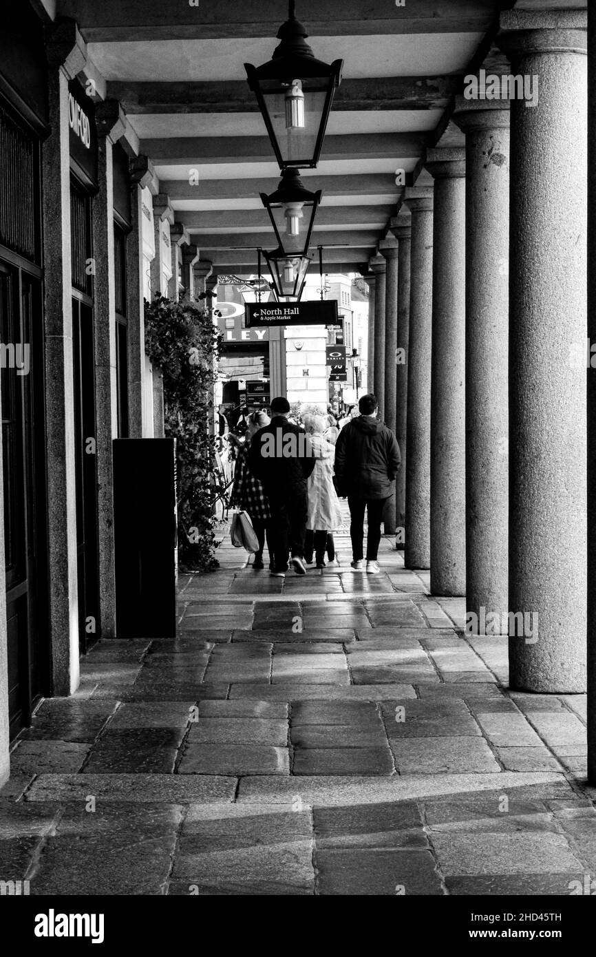 Vertikale Aufnahme von Menschen, die in der Nähe eines Hotels, Covent Gardens, London, spazieren gehen, Graustufenbild Stockfoto