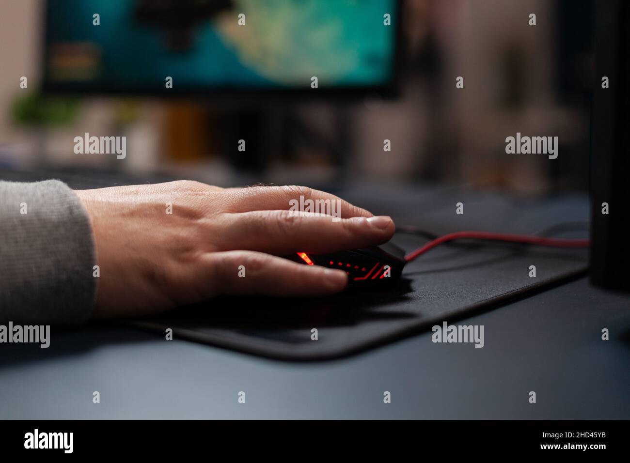Nahaufnahme des Spielers, der die Maus auf dem Mauspad hält, um Videospiele zu spielen. Mann, der Spielgeräte am Computer benutzt, spielt Online-Spiele am Schreibtisch. Hand des Spielers auf Gadget Spaß mit Spielen Stockfoto