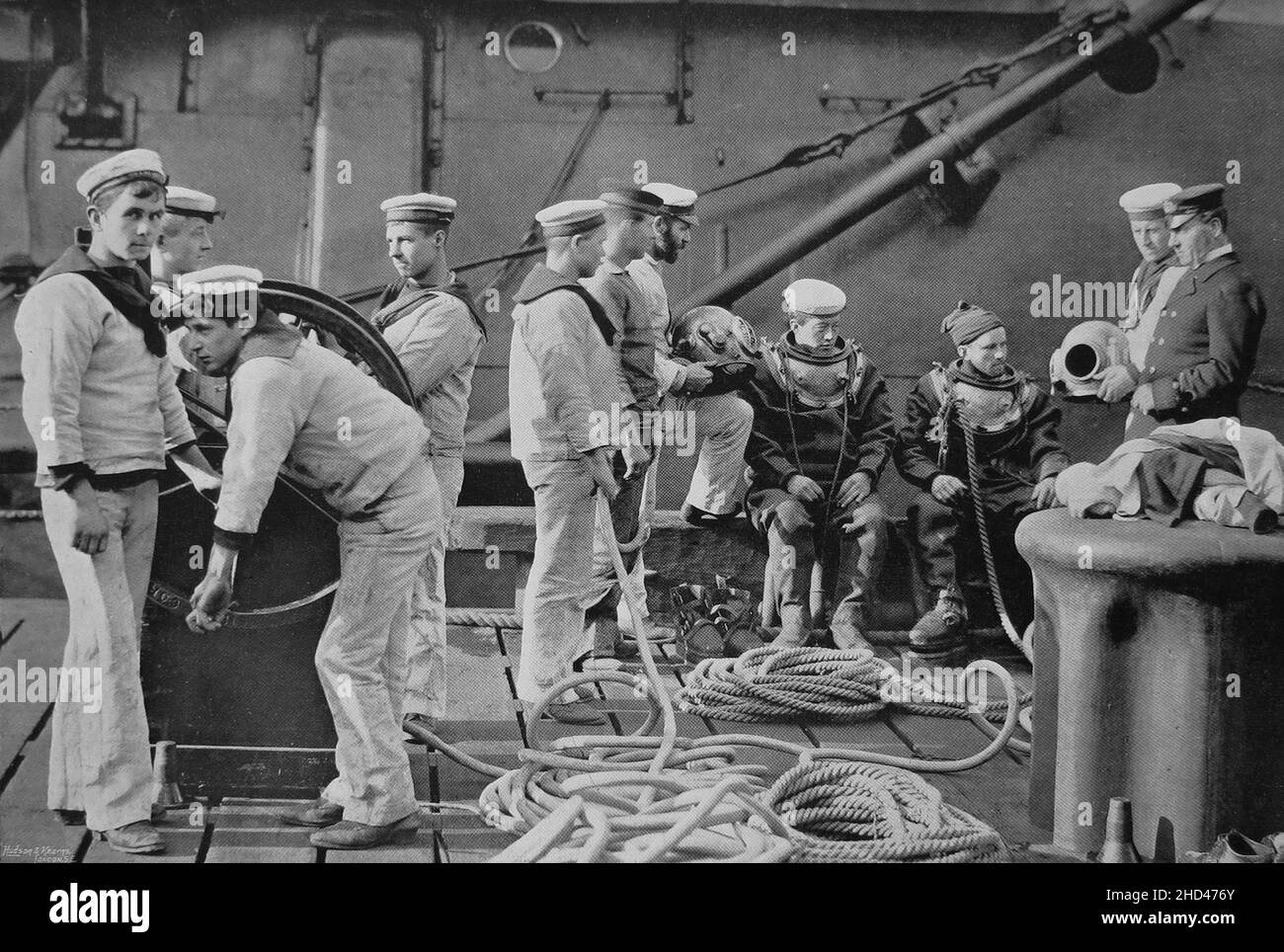 „der „der Abunter an Bord“. Circa. 1895. Der Abtauch ist mit seiner Ausrüstung aus Helm, Kleid und Luftschläuchen eine wichtige Institution an Bord des modernen Kriegsmannes, wo seine Dienste oft von höchster Nützlichkeit und Bedeutung sind. Er steht in jedem Notfall zur Verfügung, sei es zum Löschen einer verschmutzten Schraube, zur Untersuchung des Schiffs unter Wasser nach der Verseilung oder Kollision oder in flachen Gewässern, um alles, was sich verirrt hat, wiederzufinden - von einer nicht verschifften eisernen Gangway-Leiter bis zu einem fehlenden Torpedo. Stockfoto