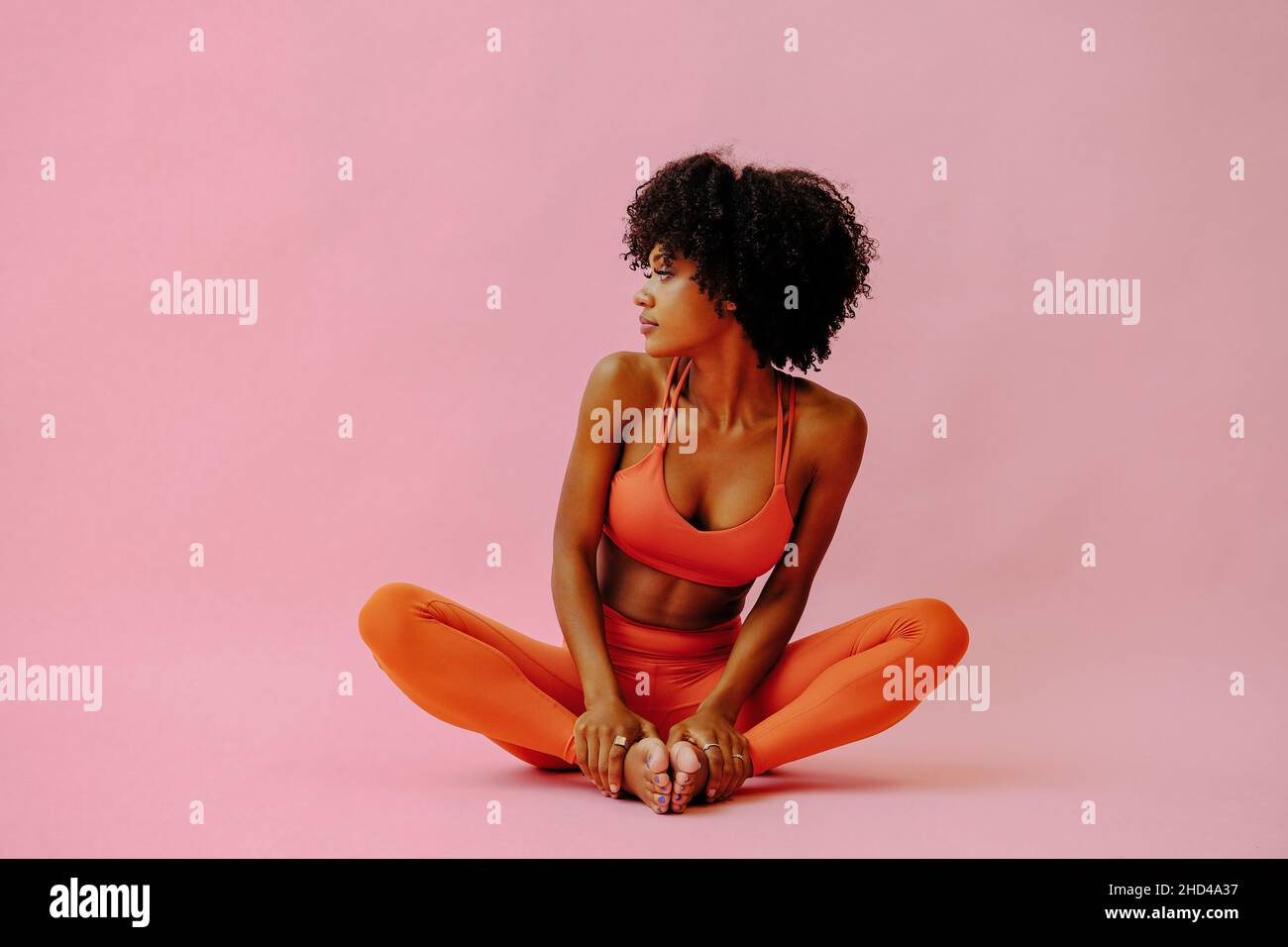 Schöne afroamerikanische Frau meditiert im Sport-Outfit auf rosa Hintergrund Stockfoto