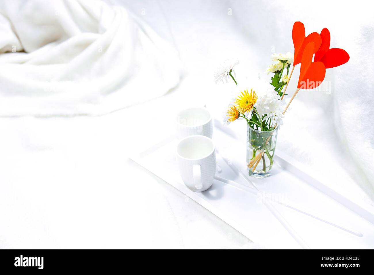 Romantisches Frühstück im weißen Bett mit Blumenvase und zwei Tassen für ein junges Paar, entspannen Sie sich Zeit im Honigmond. Stockfoto