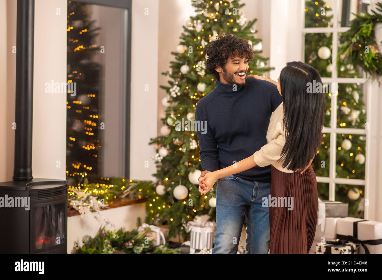 Mann tanzt mit Frau drinnen mit Weihnachtsdekoration Stockfoto