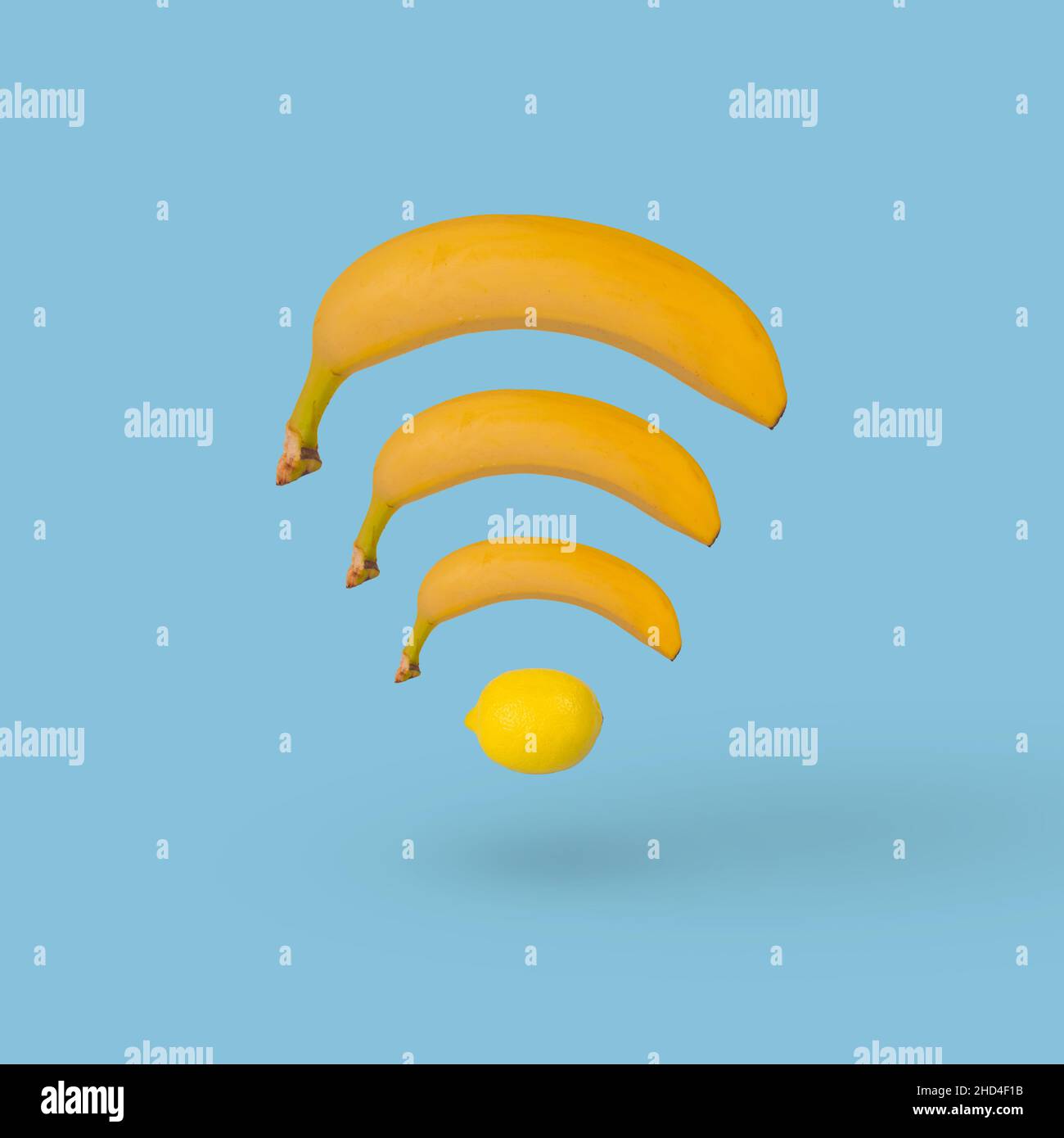 Kreatives Wi-Fi-Symbol isoliert auf blauem Hintergrund aus Banane und Zitrone. Abstrakte Fruit WiFi Wireless-Netzwerkverbindung. Stockfoto