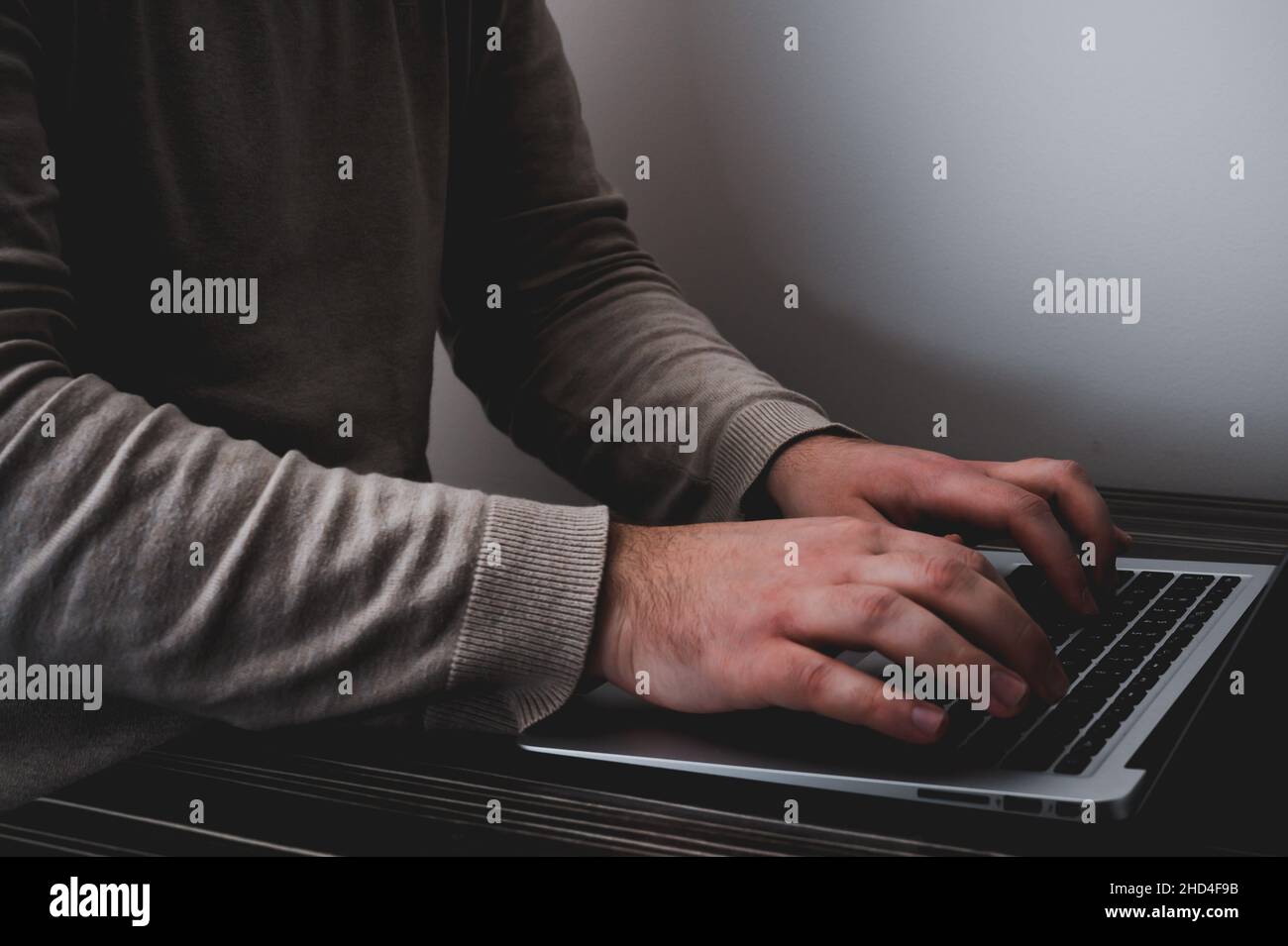 Geschäftsmann, der am Laptop für ein neues Projekt arbeitet. Laptop auf dem Holztisch. Unscharfer Hintergrund, horizontales Modell. Stockfoto