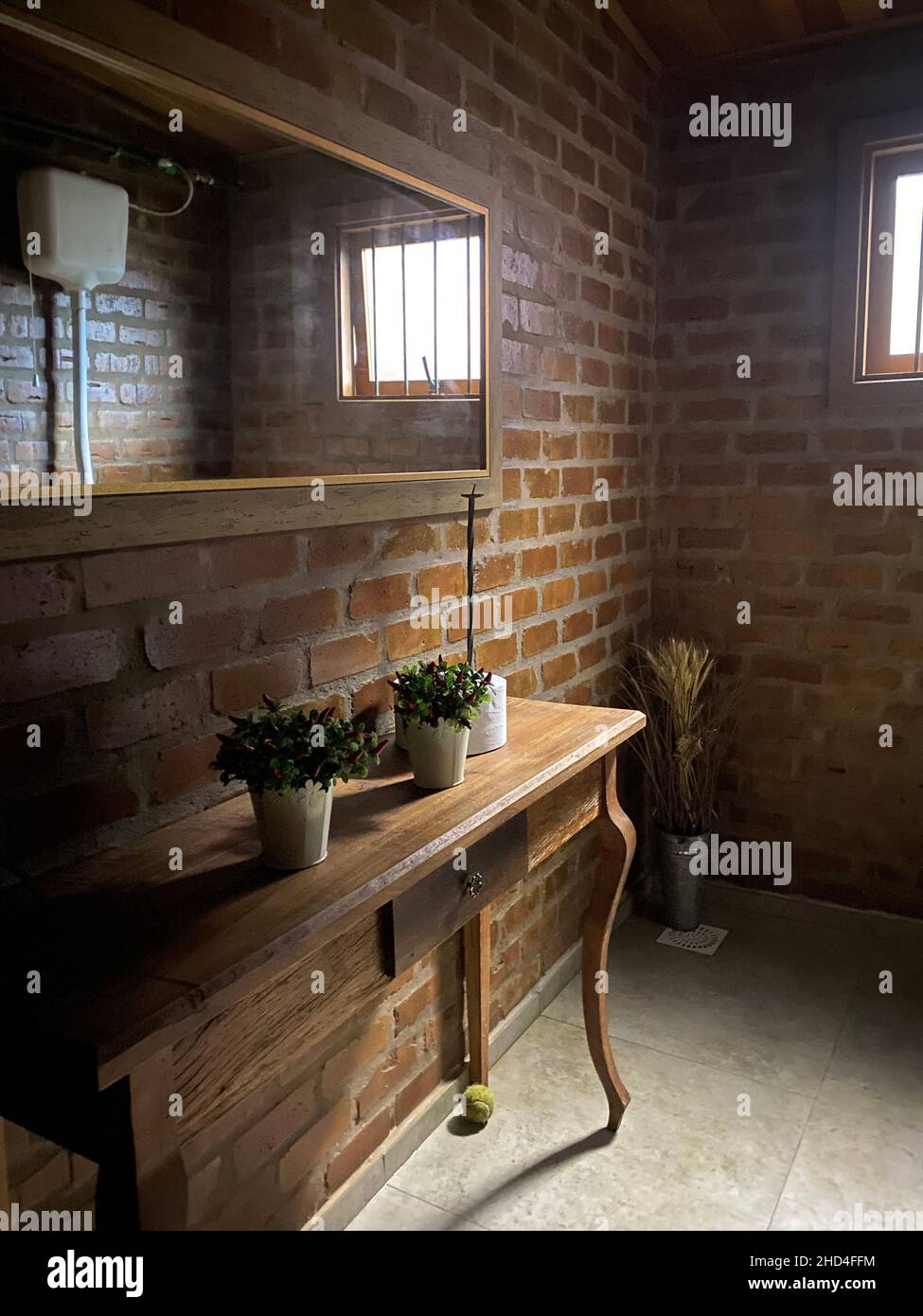 Ein sauberer Stil für die Toilette, ein Spiel von Licht und Schatten runden die Szene ab. Holzmöbel, Spiegel, einfache Linien, minimalistischer Stil. Stockfoto