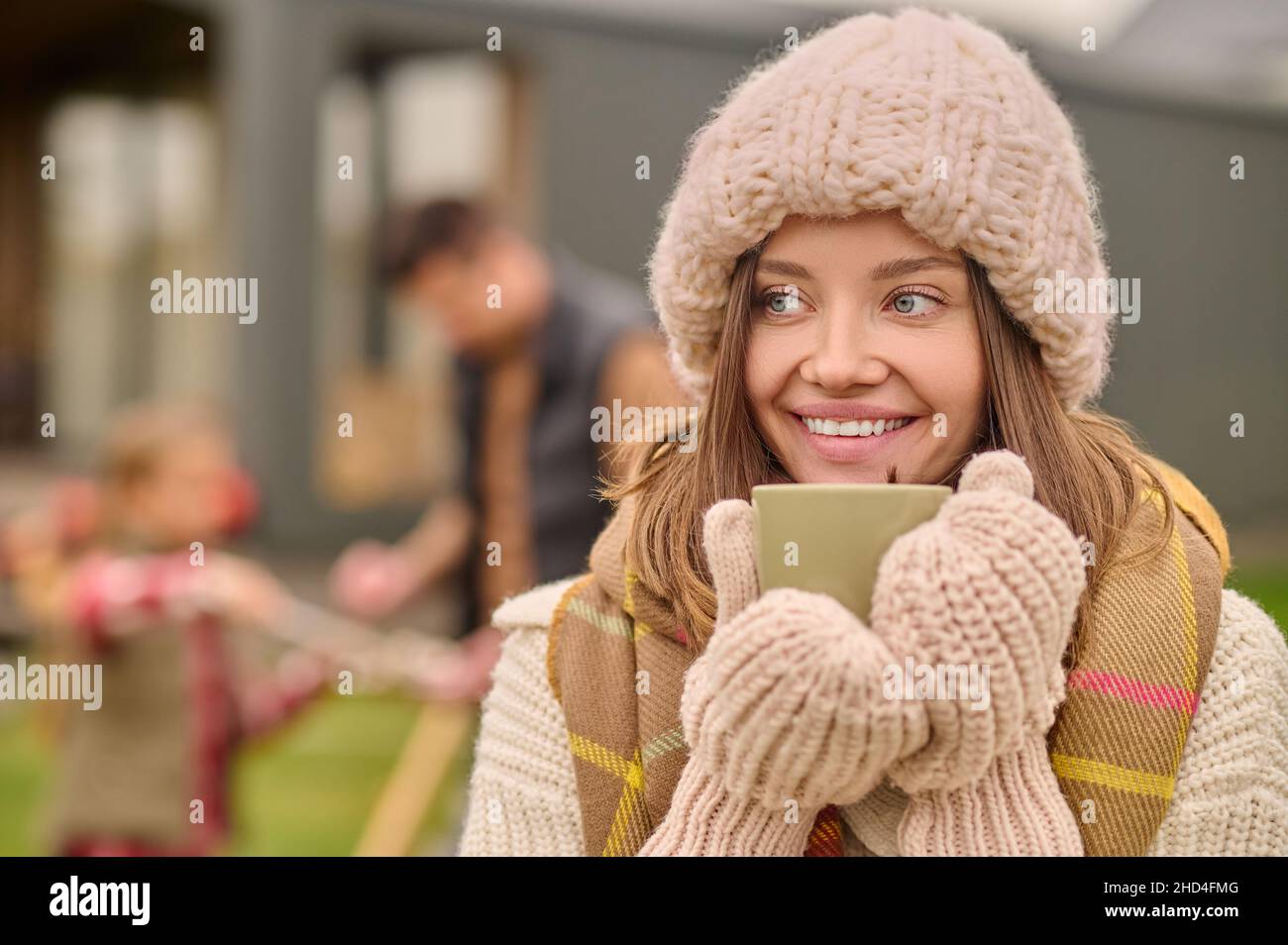 Frau in warmer Kleidung mit Tasse zur Seite schauen Stockfoto