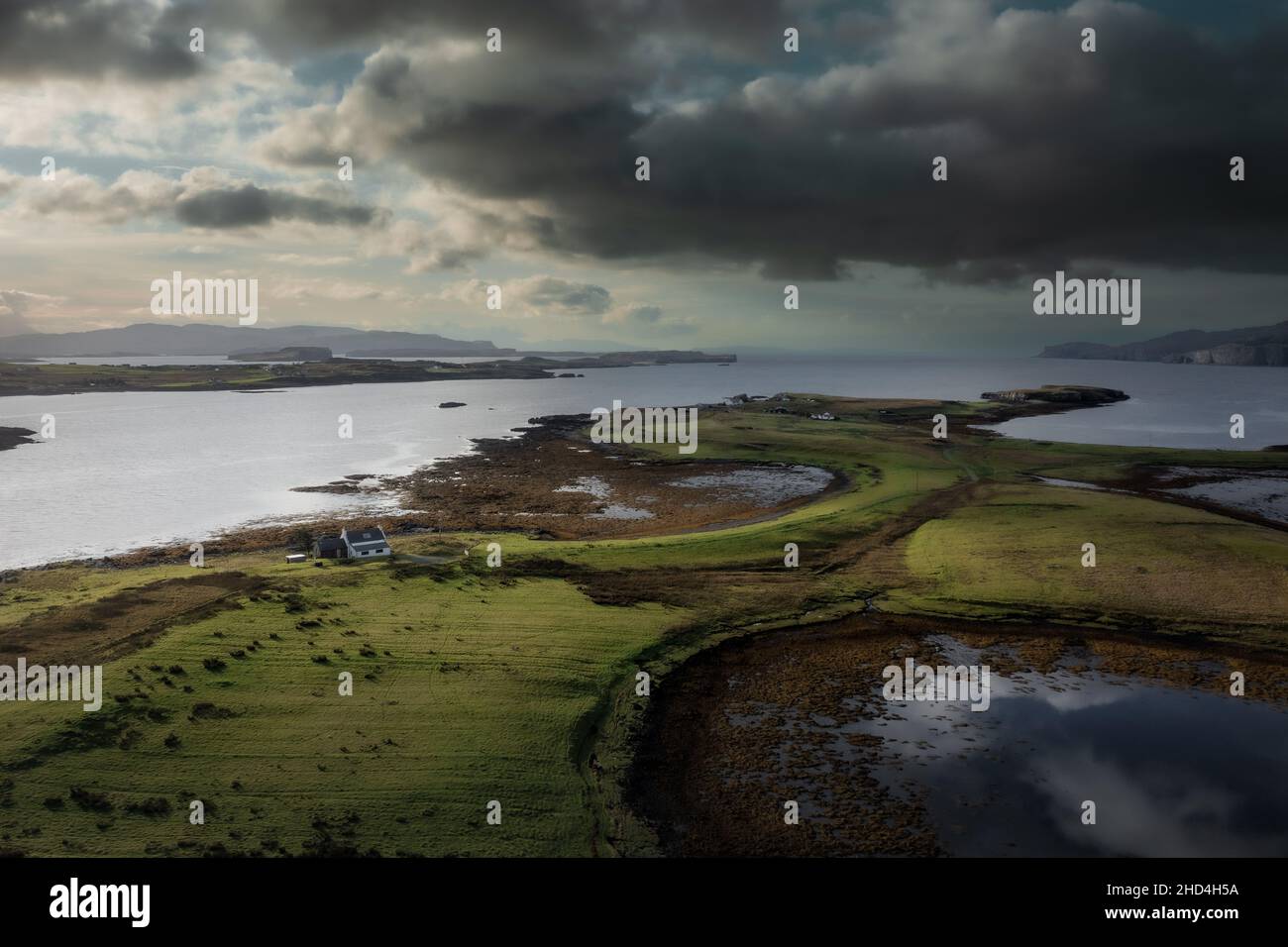 Luftaufnahme der Isle of Skye mit dramatischen Wolken und Wetter, ein Bauernhaus auf einer kleinen Insel, umgeben von Wasser Stockfoto