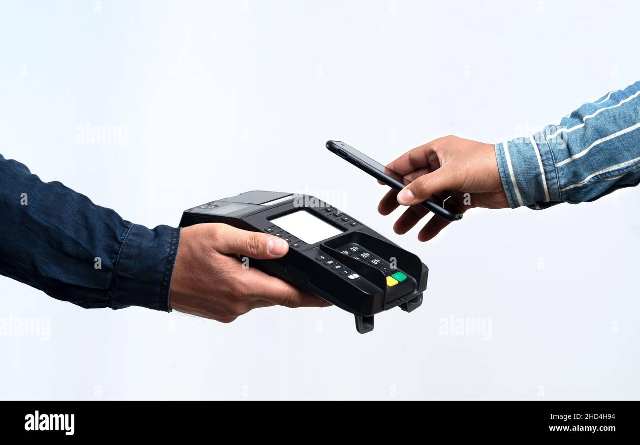 Hände halten POS-Gerät und Smartphone auf isoliertem weißem Hintergrund. Kontaktloses und einfaches Zahlungskonzept. Stockfoto
