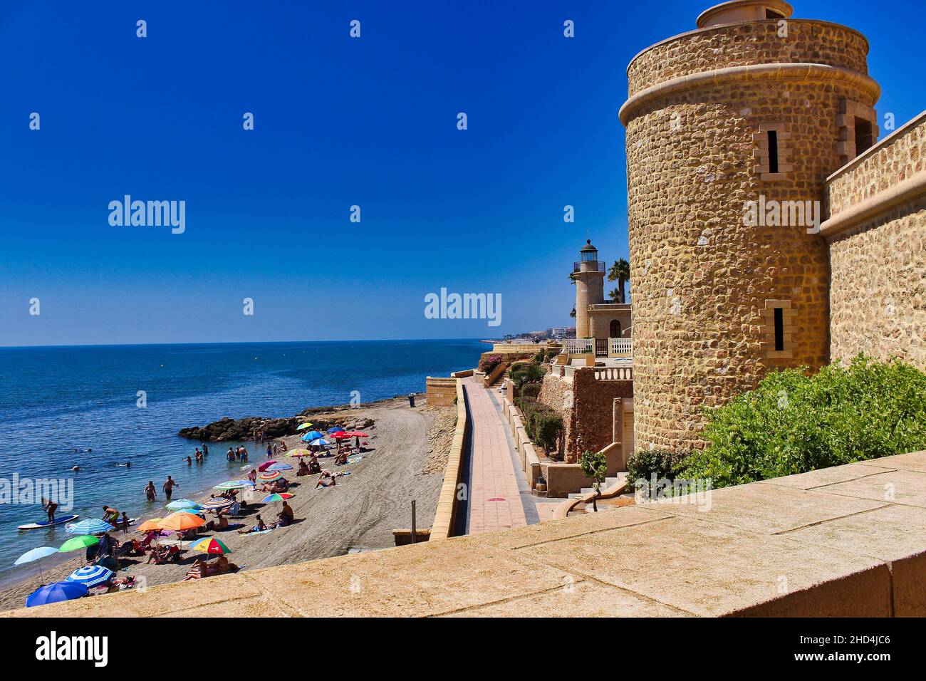 Schloss von Santa Ana mit dem Ufer des Strandes voller Menschen, Roquetas de Mar, Almeria, Andalusien, Spanien. Stockfoto