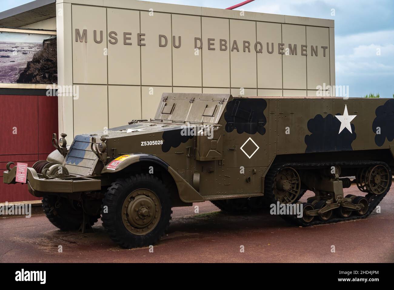 Arromanches, Frankreich - 2. August 2021: Musee du Debarquement - Übersetzung: Landing Museum. Gepanzertes US-Militärfahrzeug vor dem Gebäude. Stockfoto