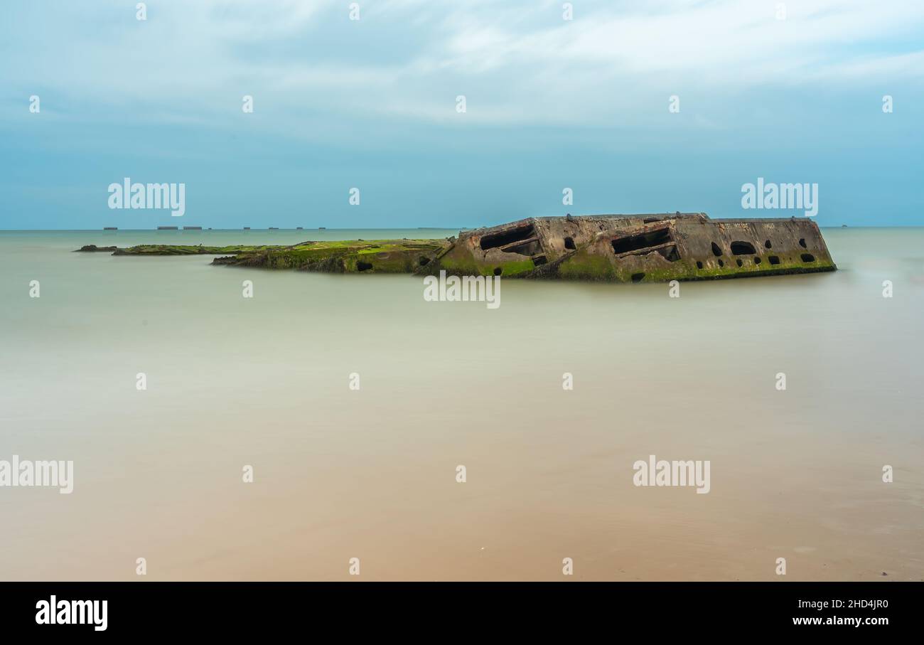 Arromanches, Frankreich - 2. August 2021: Überreste eines künstlichen militärischen Landungshafens in Arromanches in der Normandie - Langzeitbelichtung Stockfoto