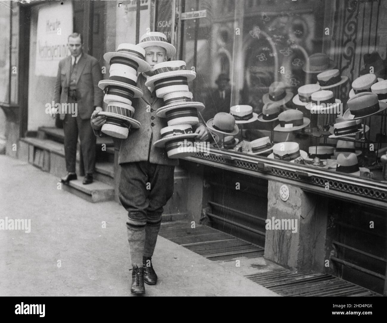 Vintage Pressefoto aus dem frühen 20th. Jahrhundert: Junger Mann außerhalb des Hutladens mit Bootsfahrern Stockfoto