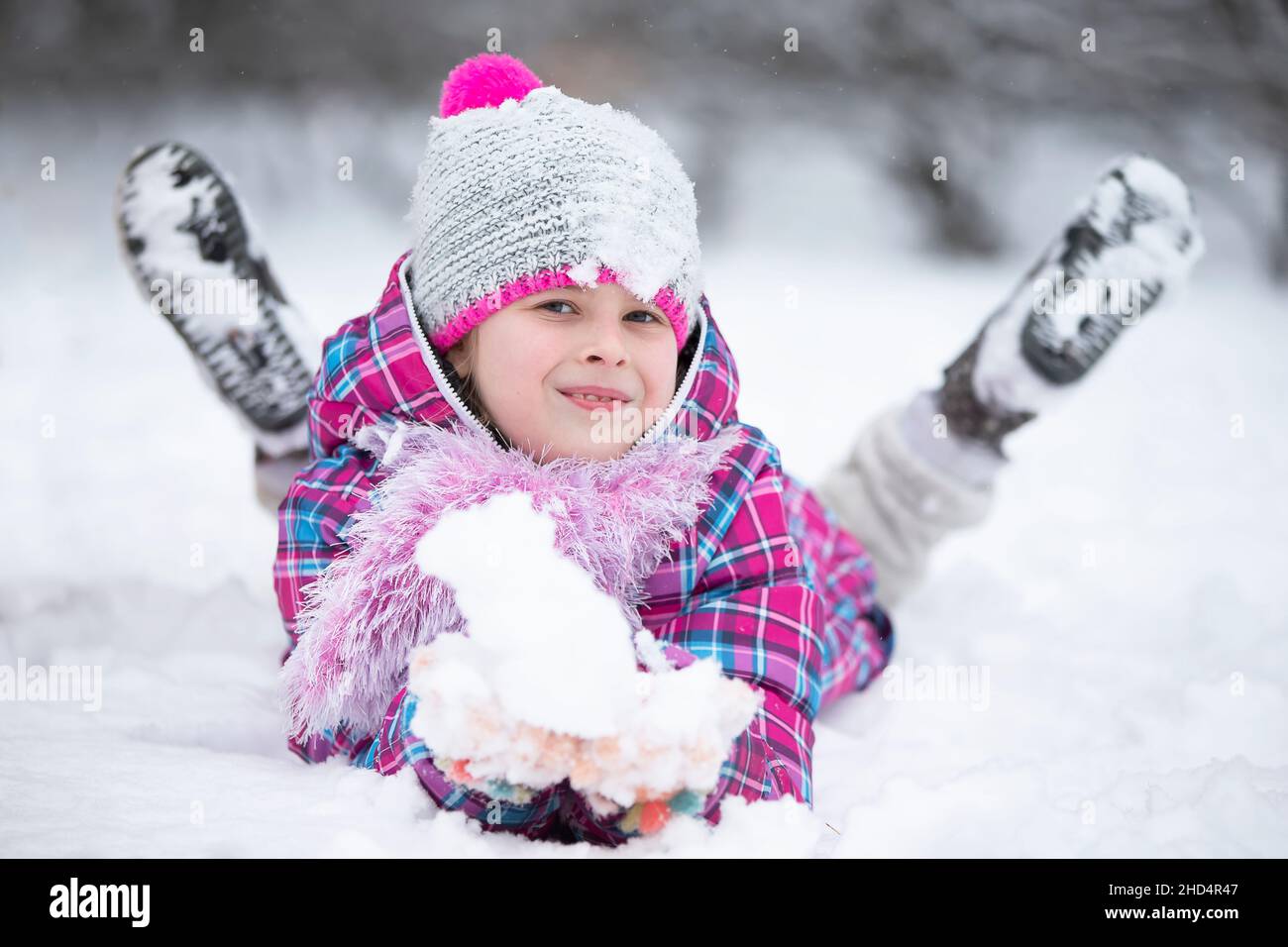 Glückliches Mädchen wirft Schnee. Das Kind freut sich im Winter und den ersten Schnee. Stockfoto