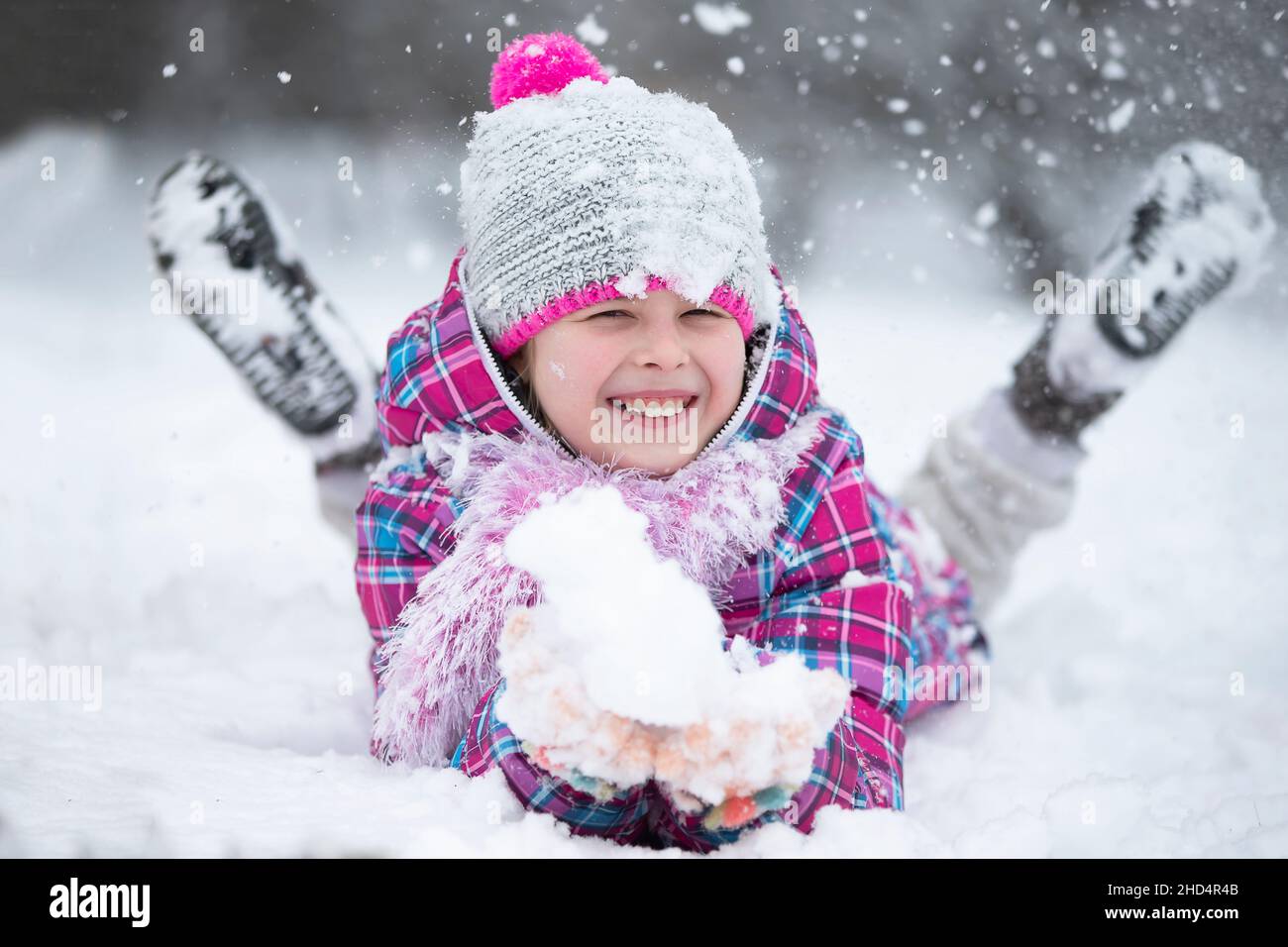 Glückliches Mädchen wirft Schnee. Das Kind freut sich im Winter und den ersten Schnee. Stockfoto