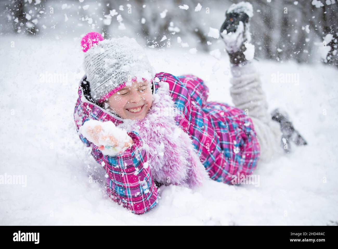 Glückliches Mädchen wirft Schnee. Das Kind freut sich im Winter und den ersten Schnee. Stockfoto