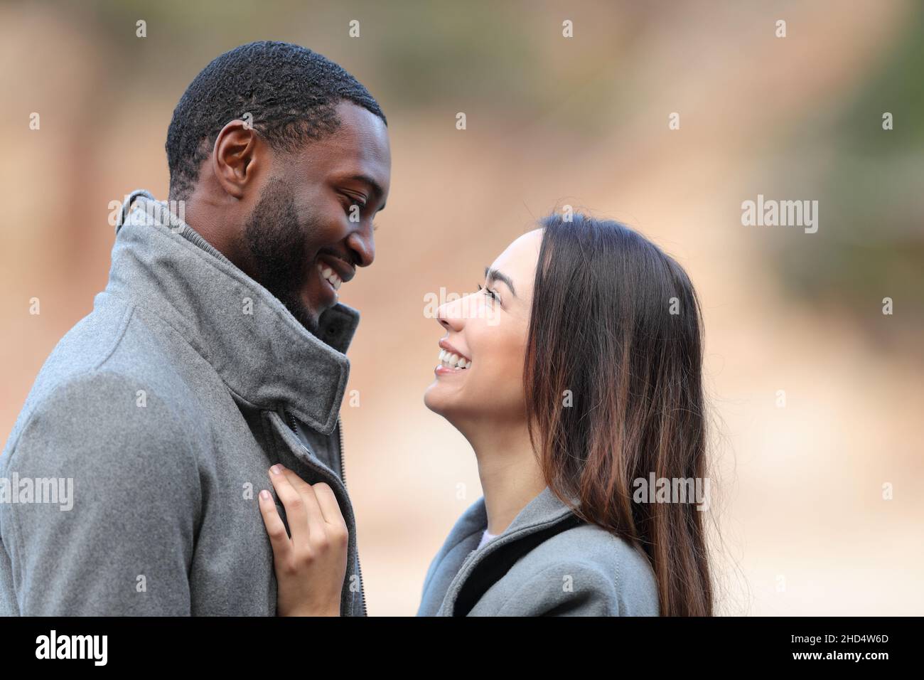 Seitenansicht Porträt eines glücklichen interrassischen Paares, das im Winter verliebt flirtet Stockfoto