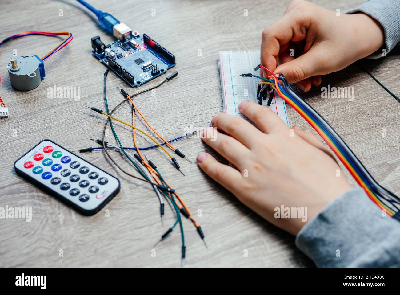 Ein Kind, das Kabel an Sensorchips ansteckt, während es arduino Codierung und Robotik lernt Stockfoto