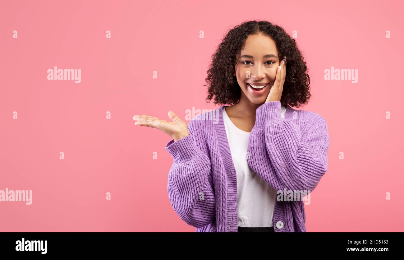Tolles Angebot, tolle Promo. Coole, tausendjährige schwarze Frau, die Kopierraum vor pinkem Studiohintergrund zeigt Stockfoto