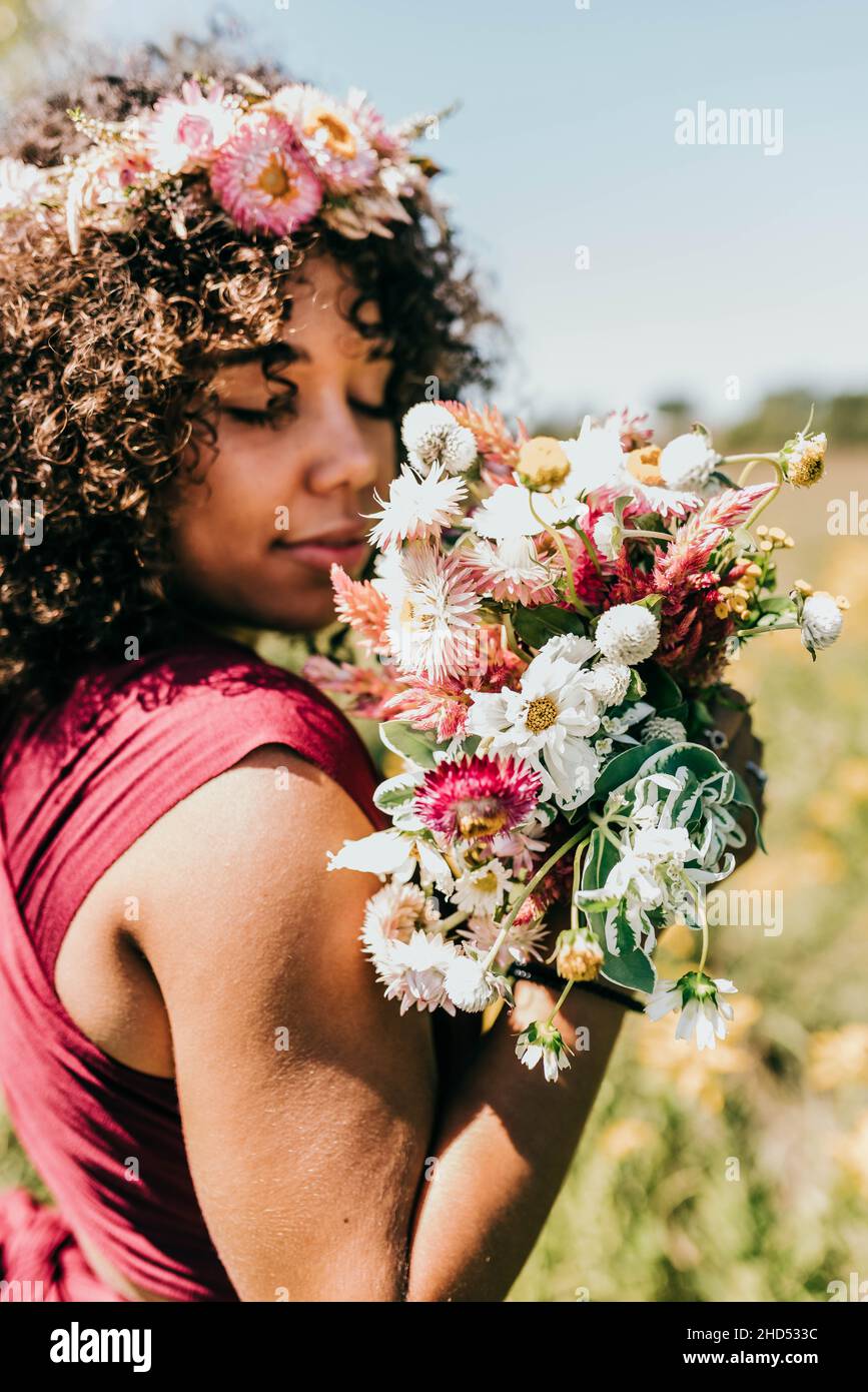 Die schwarze Frau hält einen Strauß rosa Blumen bis ins Gesicht Stockfoto