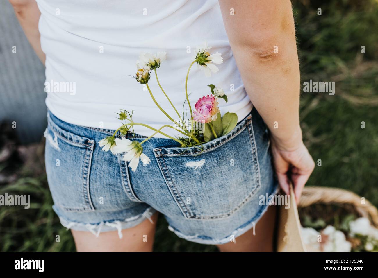Ein Strauß Wildblumen in der Gesäßtasche aus blauen jean-Shorts Stockfoto