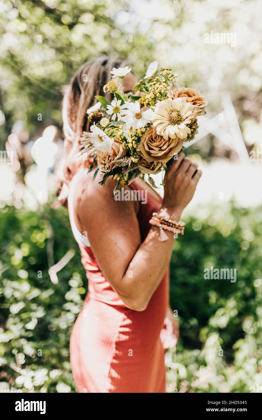 Weiße Frau hält frisch gepflückte Blumen vor dem Gesicht Stockfoto