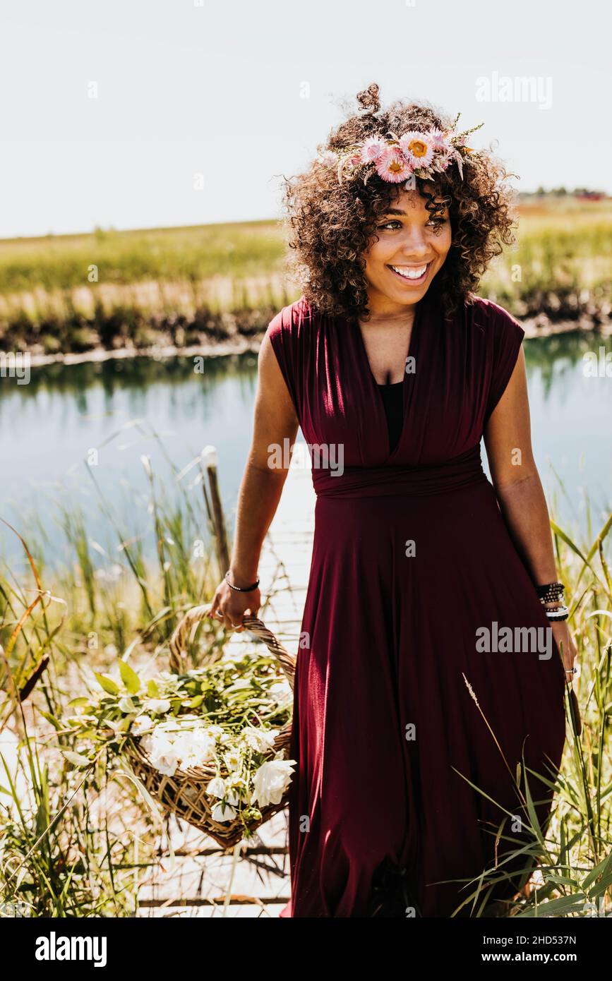 Schwarze Frau trägt Blumenkrone geht vom Dock in der Nähe des Teiches Stockfoto