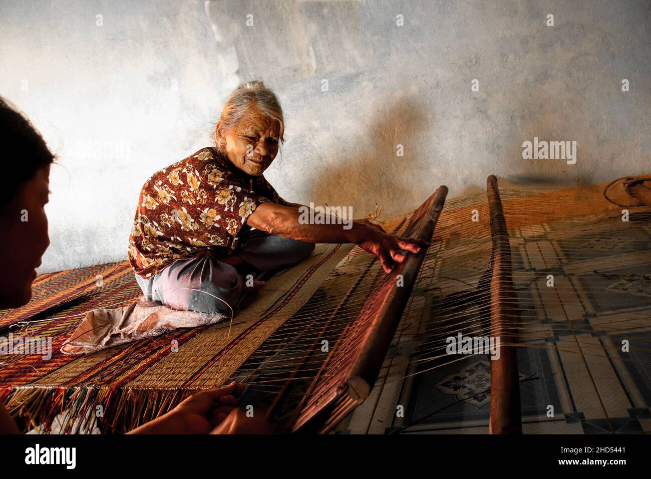 Alte Frau, die in Duy Vinh Village, Vietnam, eine traditionelle Segge webt Stockfoto