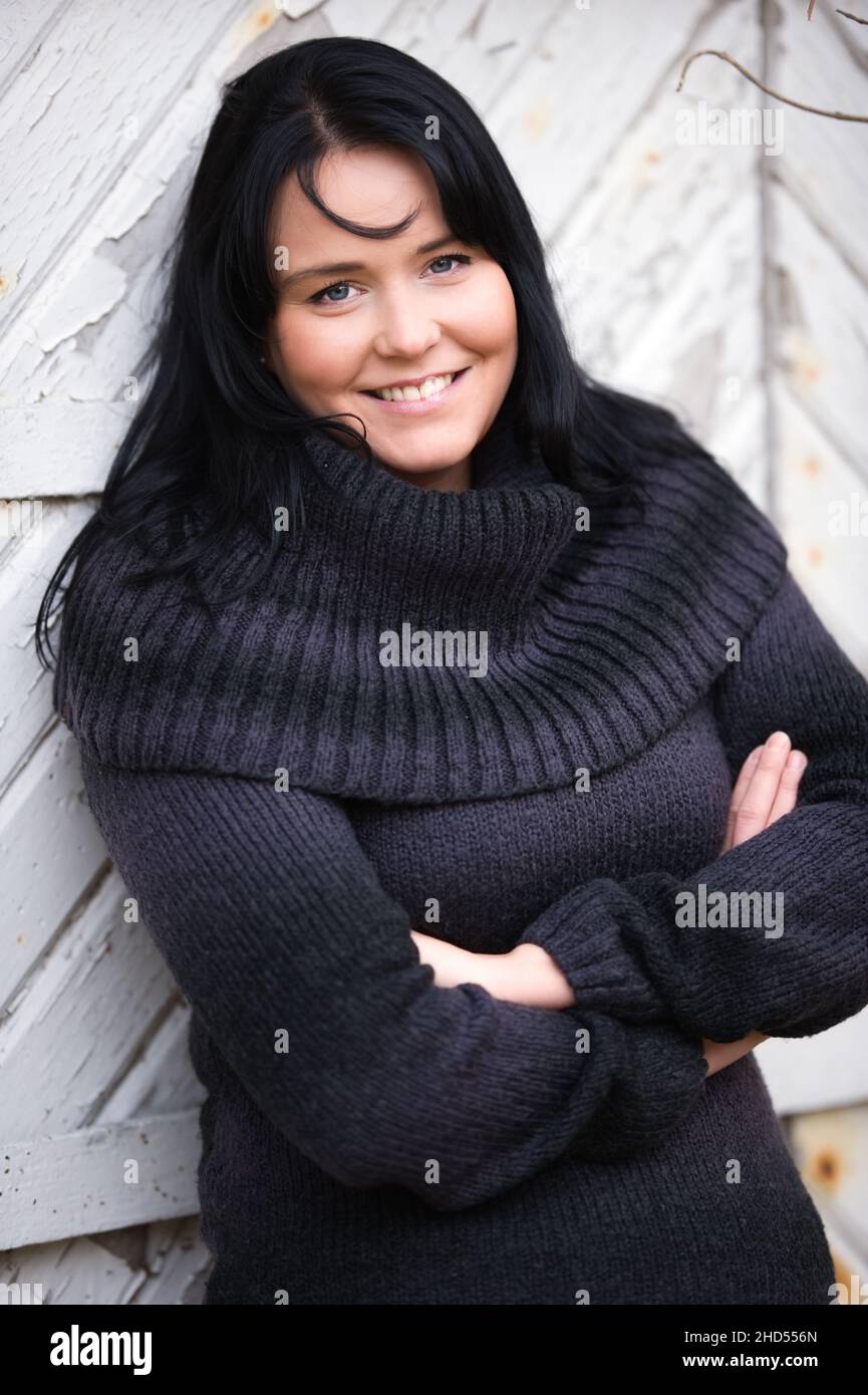 Porträt einer Frau mit gekreuzten Armen vor einer alten Holztür. Stockfoto