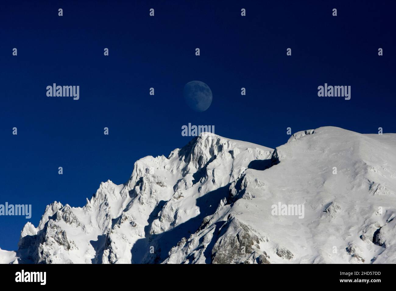 Mond setzt sich über dem schneebedeckten Berg Maglic in Bosnien nieder. Stockfoto