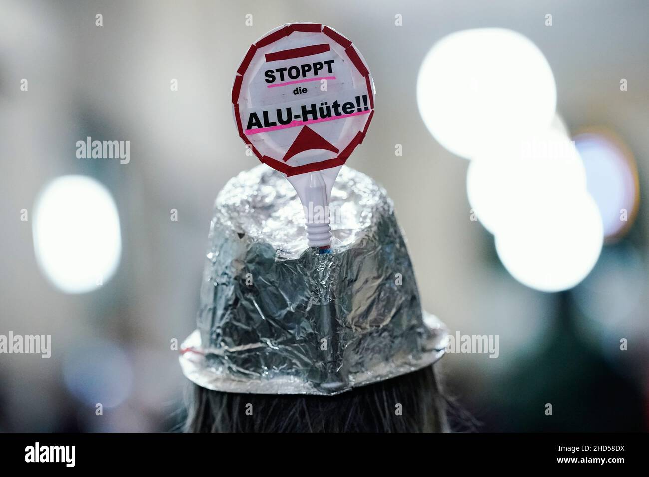 Mannheim, Deutschland. 03rd Januar 2022. Ein Teilnehmer trägt einen silbernen Hut mit der Aufschrift „Stoppt die Alu-Hüte!!!“ Nimmt an einer Menschenkette rund um das Rathaus Teil, als Zeichen gegen Märsche von Gegnern der Corona-Politik und für mehr Solidarität in der Pandemie. Quelle: Uwe Anspach/dpa/Alamy Live News Stockfoto