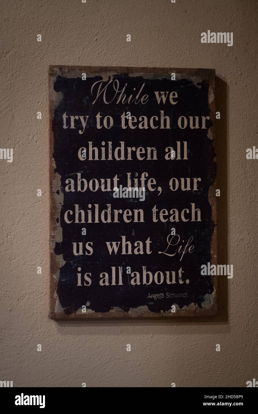 An der Wand steht: „während wir versuchen, unseren Kindern alles über das Leben zu vermitteln, lehren uns unsere Kinder, worum es im Leben geht. Lektionen aus dem Leben. Zitat Stockfoto