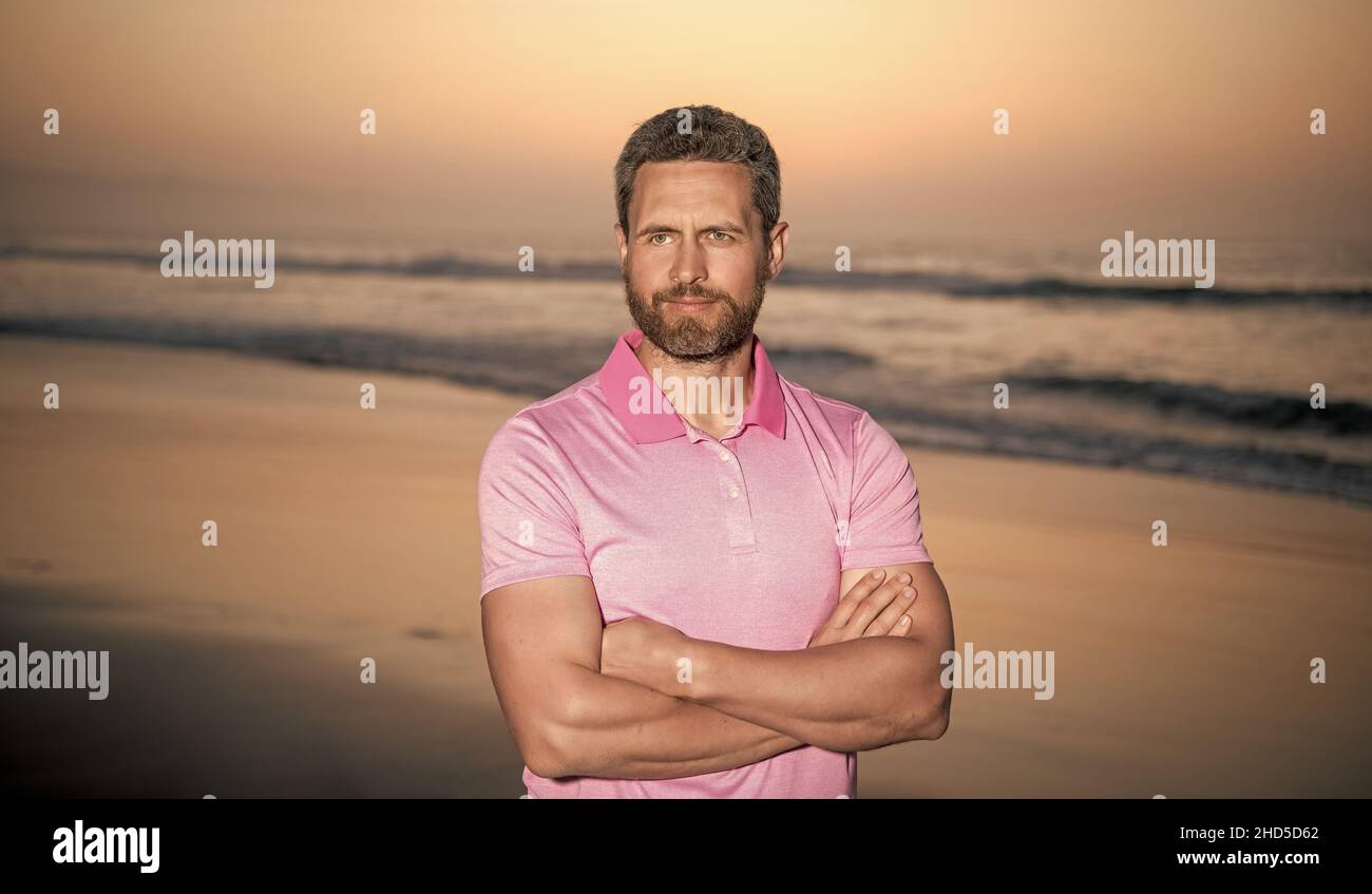Sommerurlaub. Schöner Mann mit Bart im Sonnenuntergang über dem Meer. Unrasiert Kerl am Morgen Strand Stockfoto