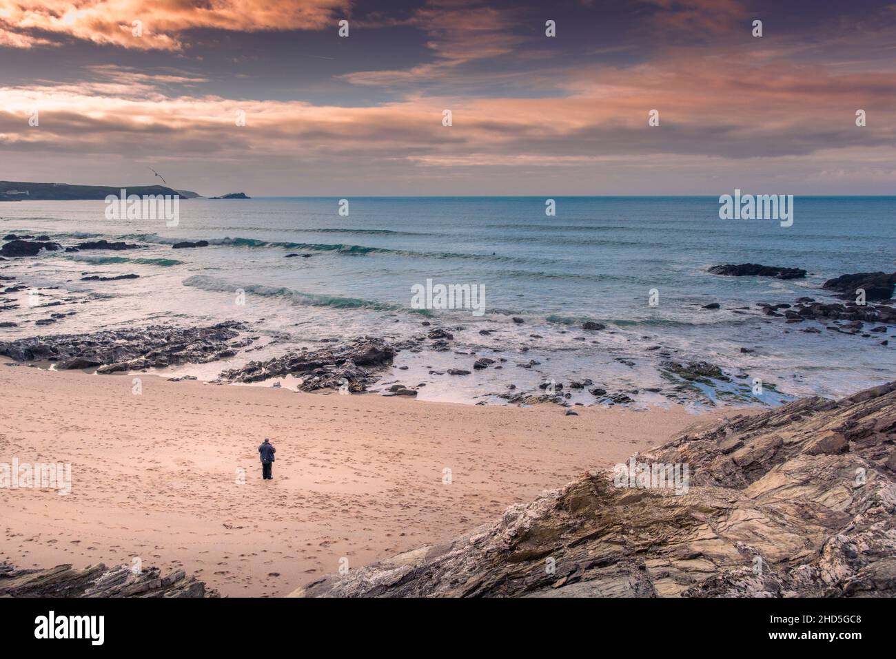 Ein Mann, der allein am Strand von Little Fistral in Newquay in Cornwall steht. Stockfoto