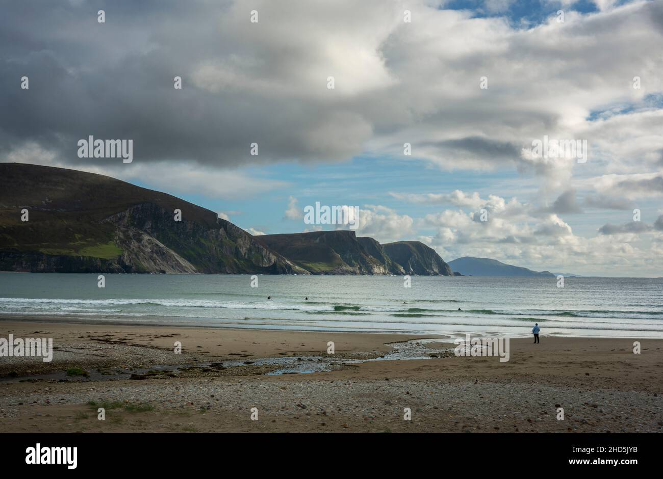 Eine Person beobachtet einige Schwimmer am wunderschönen Keel Beach mit den Minaun Cliffs auf Achill Island im County Mayo in Irland Stockfoto