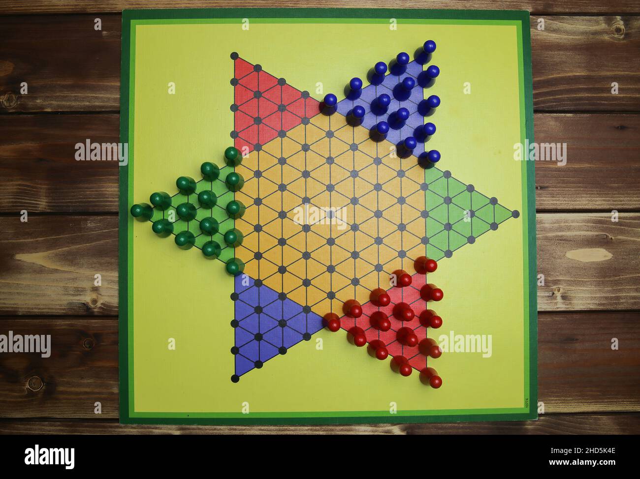 Ansicht von oben nach unten auf isoliertem gelben Gamboard mit Sechseck, bunten Spielsteinen, Holzhintergrund - chinesische Dame (Sternhalma) Stockfoto