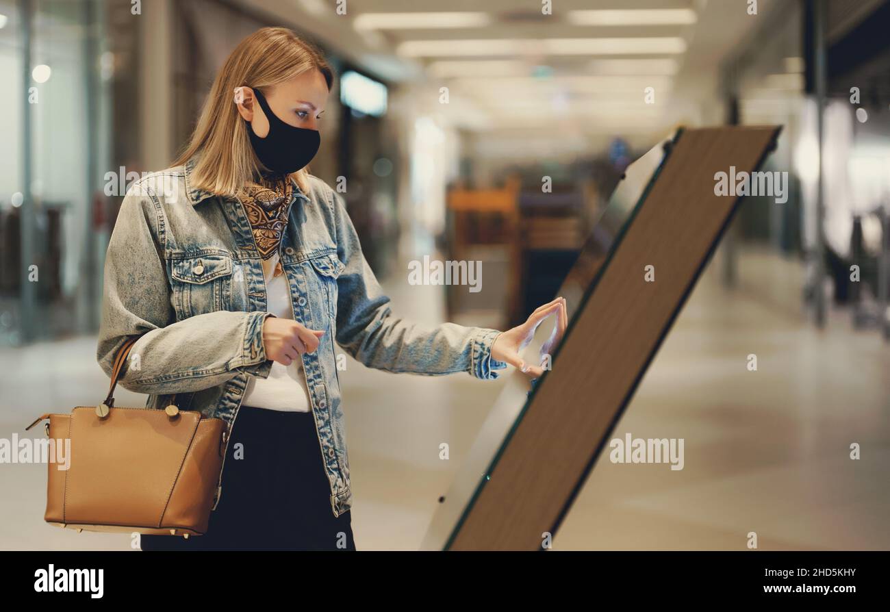 Frau, die ein Selbstbedienungsterminal im Einkaufszentrum benutzt. Stockfoto