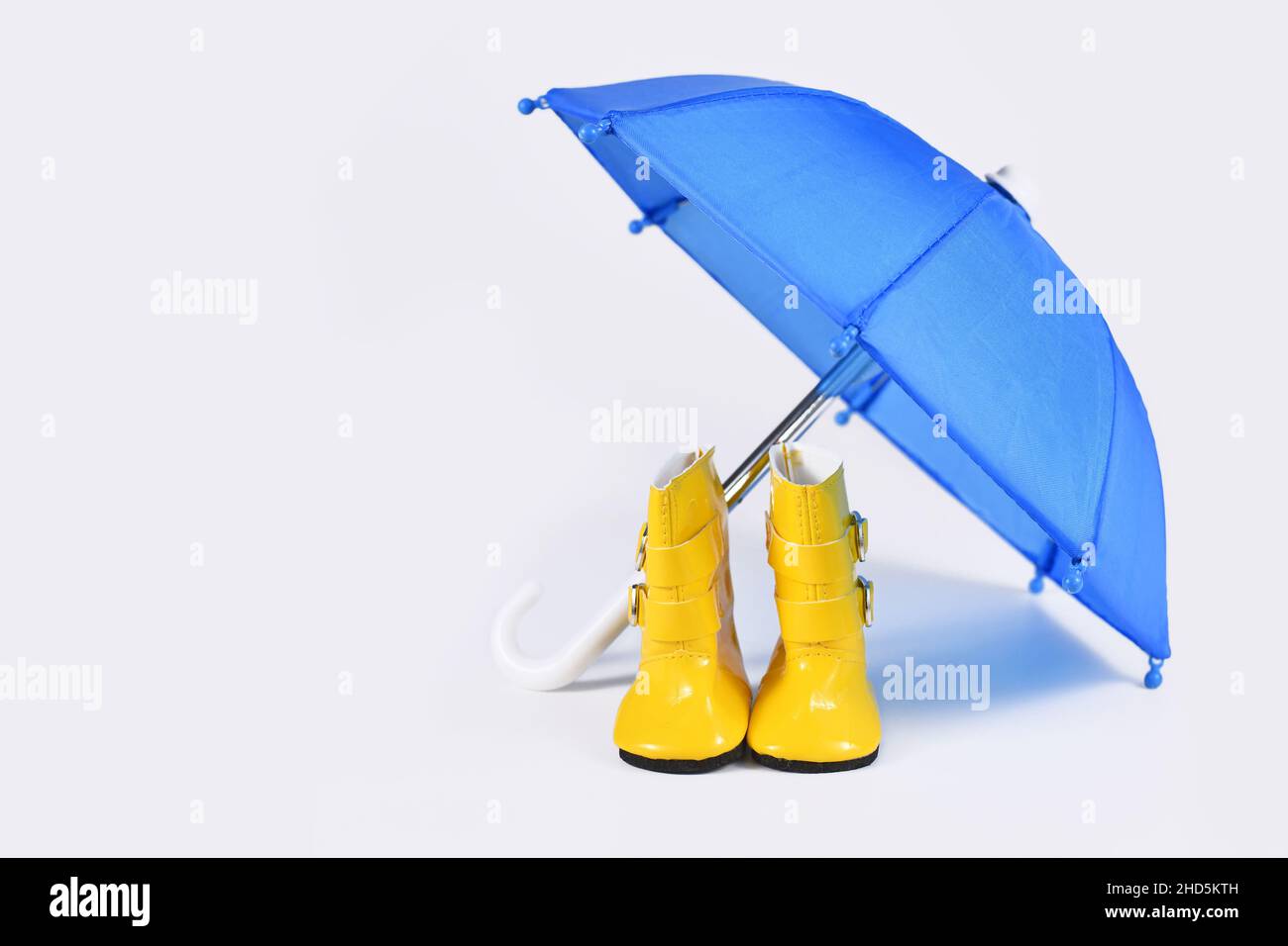 Regenkonzept mit blauem Regenschirm und gelben Gummistiefeln Stockfoto