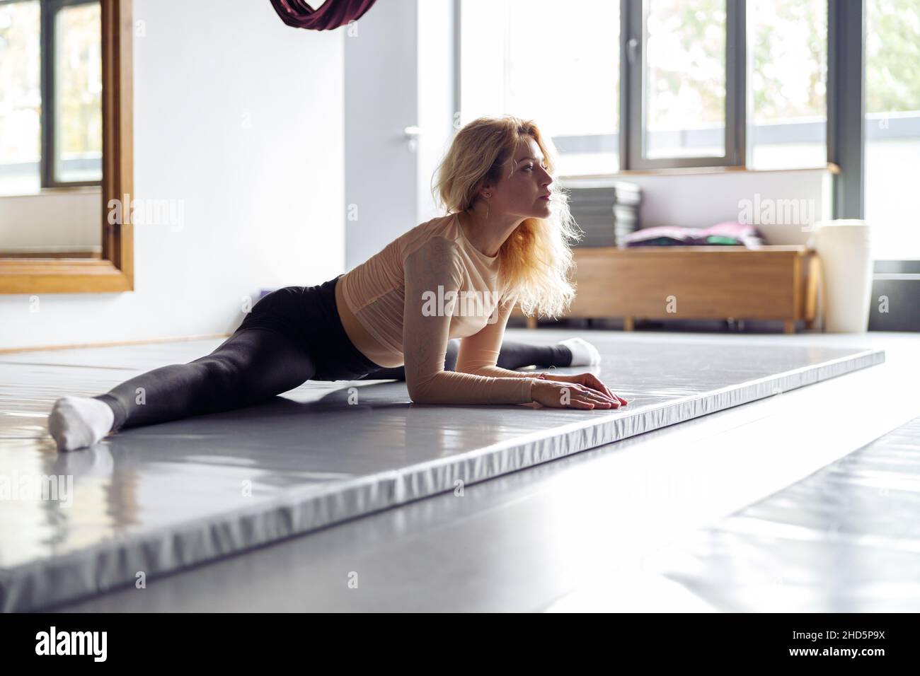 Ziemlich sportliche junge Frau sitzt und tut Split beim Training im Stretching-Studio. Gesundes Lifestyle-Konzept Stockfoto
