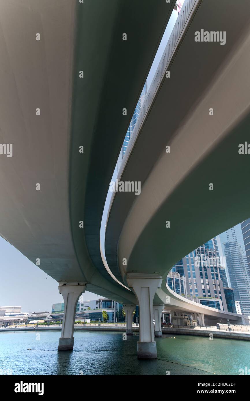 Unter einer gebogenen Betonstraßenbrücke über den Dubai Canal und das führende tp Business District Dubai Stockfoto