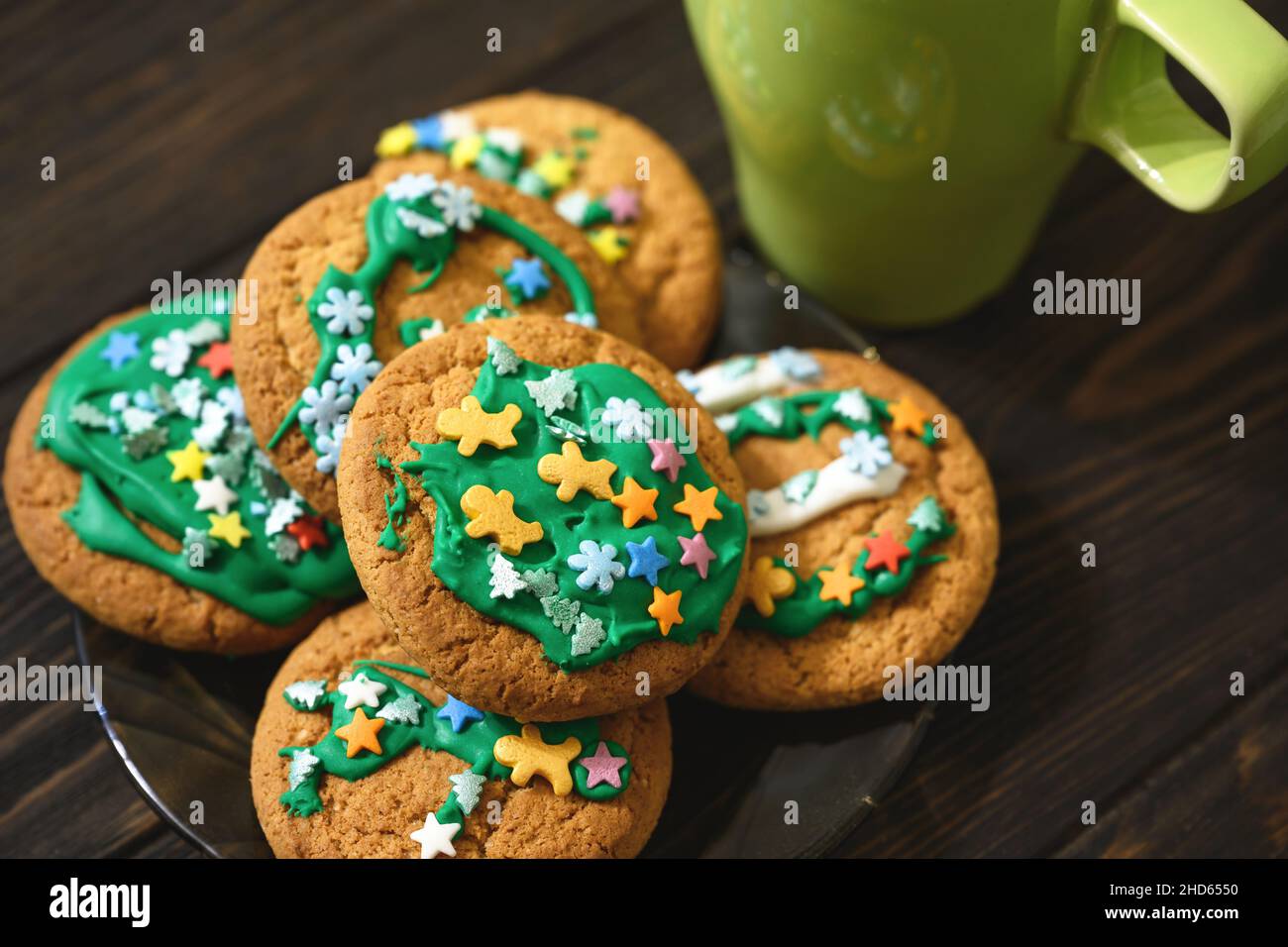 Haferflockenplätzchen auf dem Teller und Kaffeetasse auf dem Holztisch, hausgemachte Weihnachtskeks mit Zuckerglasur. Haufen von Dessert-Essen aus der Nähe, köstliche EA Stockfoto