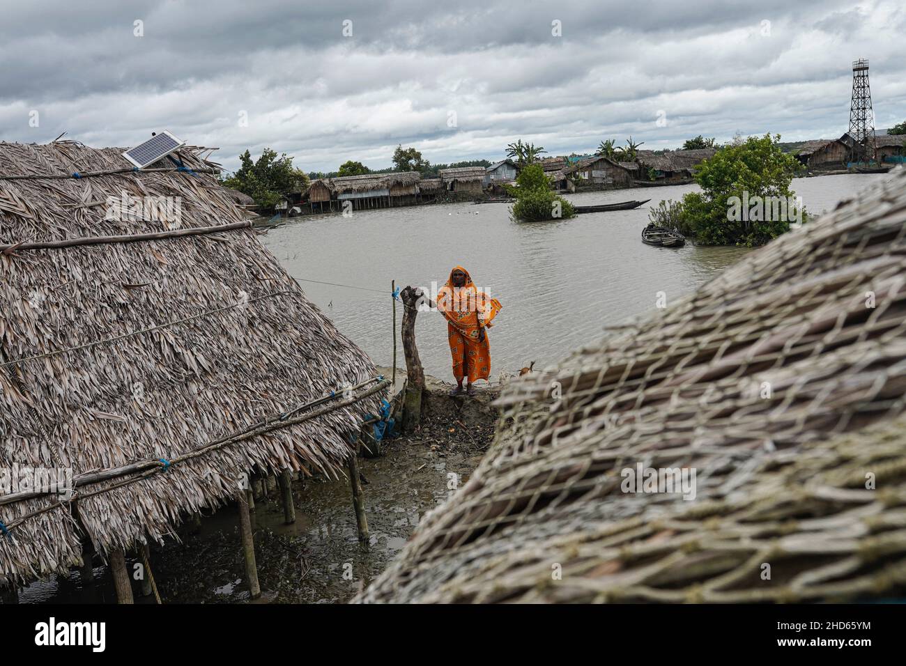 Mongla, Bangladesch. 12th September 2021. Eine Frau steht vor ihrem Haus, das aufgrund eines Wirbelsturms im Küstengebiet des Dorfes Jaymani mehrmals wiederaufgebaut wird.Bangladesch ist eines der Länder, das am stärksten von den Auswirkungen des Klimawandels betroffen ist. Die regelmäßigen und schweren Naturgefahren, die Bangladesch bereits unter tropischen Wirbelstürmen, Hochwasser, Flußerosion, Überschwemmungen, Erdrutschen und Dürren leidet, werden durch den Klimawandel immer intensiver und häufiger werden. (Bild: © Sultan Mahmud Mukut/SOPA-Bilder über ZUMA Press Wire) Stockfoto