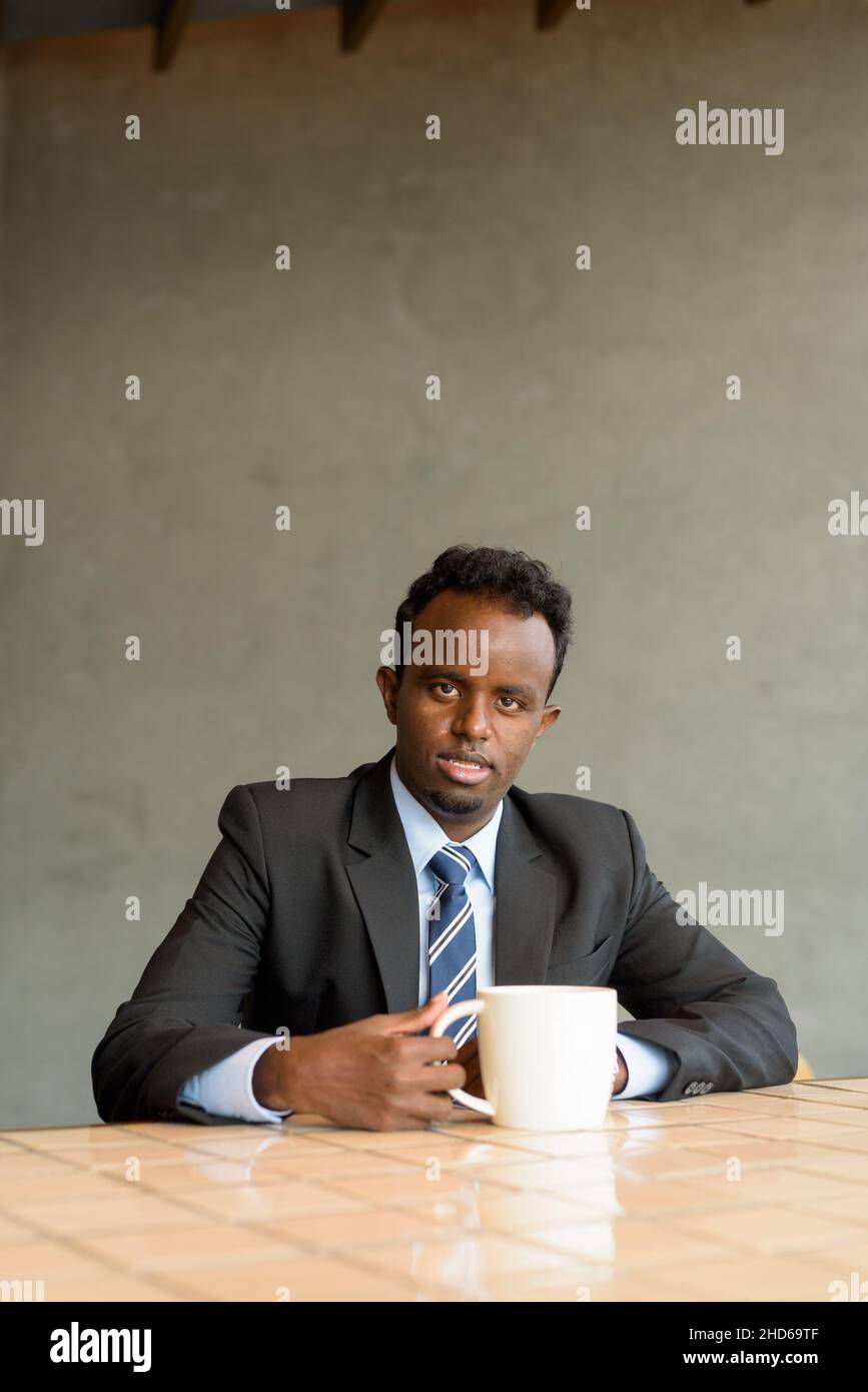 Porträt eines jungen afrikanischen Geschäftsmannes in Anzug und Krawatte im Café Stockfoto