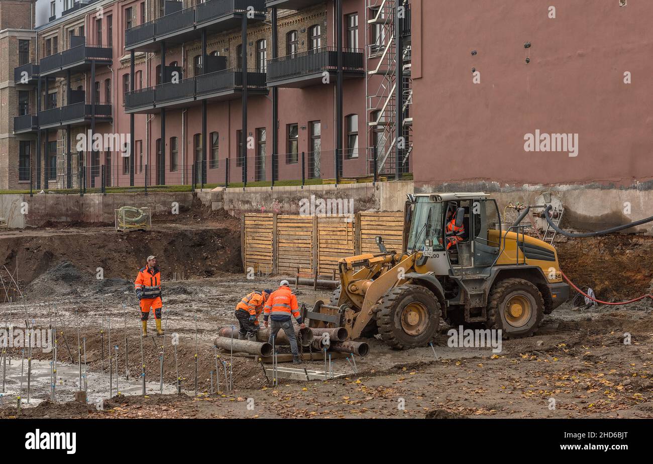 Bauarbeiter verladen alte Rohre auf einer großen Baustelle Stockfoto